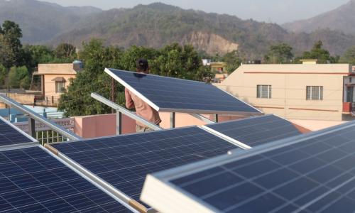 A man installs rooftop solar panels in an Indian village.