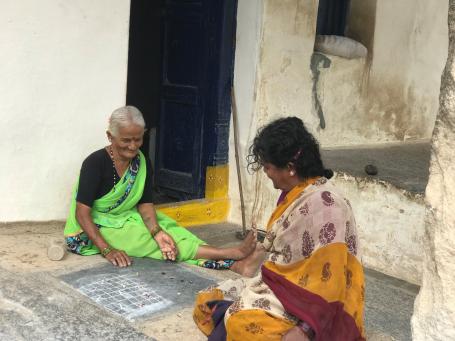 Two unemployed women play a board game on the street in India.
